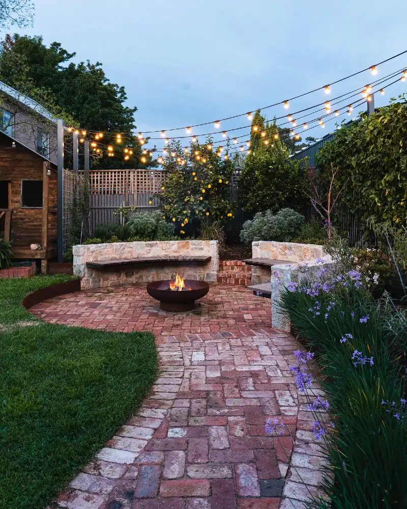 Brick Courtyard Fire Bowl with Built-In Limestone Benches and Overhead Café Lights