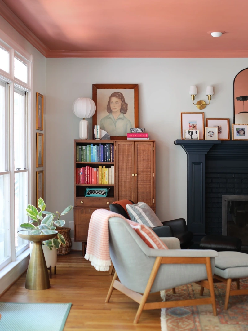 Coral Pink Painted Ceiling with Dark Charcoal Fireplace and Woven Wood Hutch
