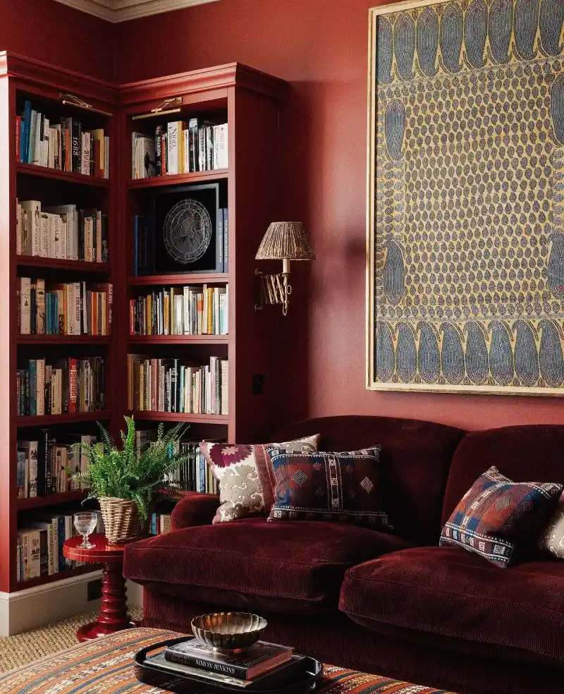 Corner Bookshelves with Burgundy Walls and Velvet Seating