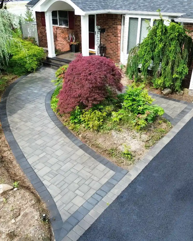 Curved Gray Paver Walkway with Dark Border and Layered Garden Island