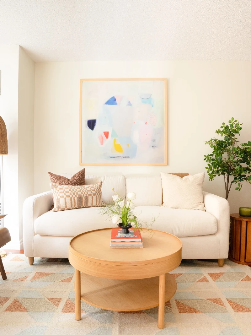 Curved White Sofa with Round Oak Coffee Table and Soft Abstract Art