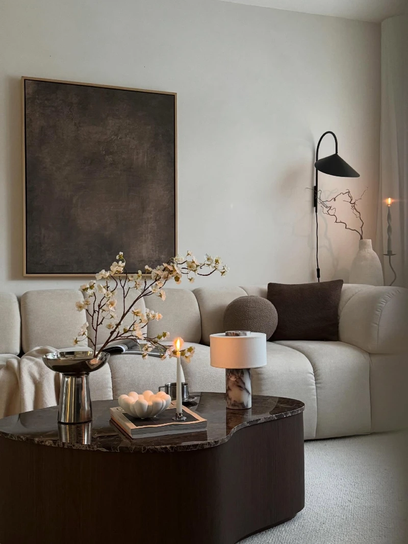 Dark Marble Organic Coffee Table with Blossom Branches and Minimalist Wall Sconce
