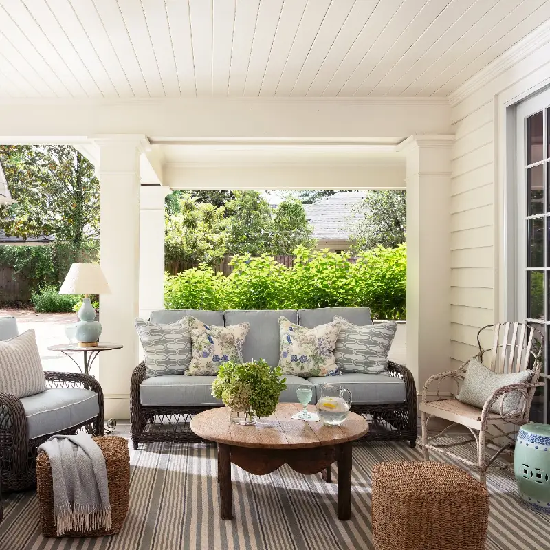 Dark Woven Sofa with Light Blue Cushions, Scalloped Wooden Coffee Table, and Striped Rug
