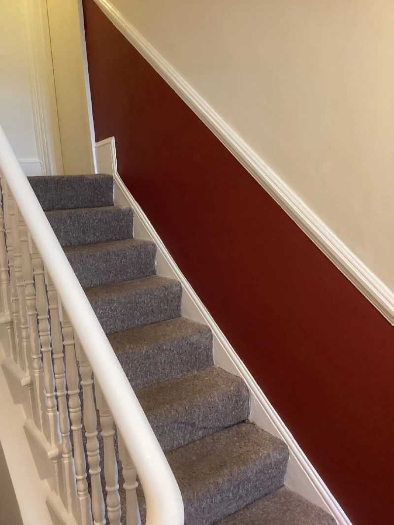 Deep Maroon Diagonal Split Staircase Wall with White Handrail and Beige Upper Section