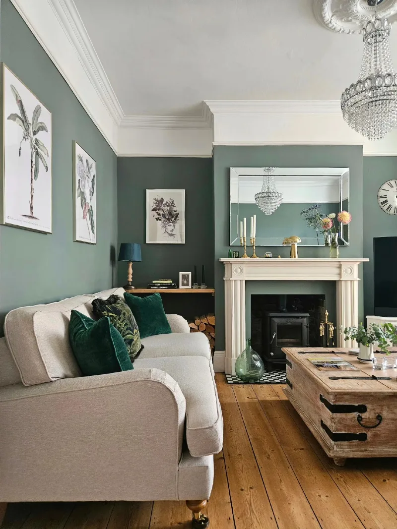 Deep Sage Green Living Room with Cream Fireplace, Crystal Chandelier, and Emerald Cushions