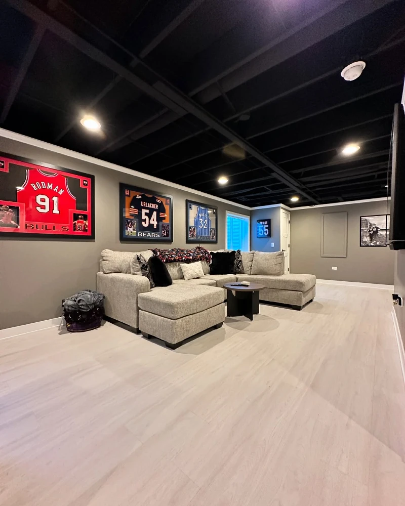 Exposed Black Joist Ceiling with L-Shaped Sectional and Multi-Jersey Gallery