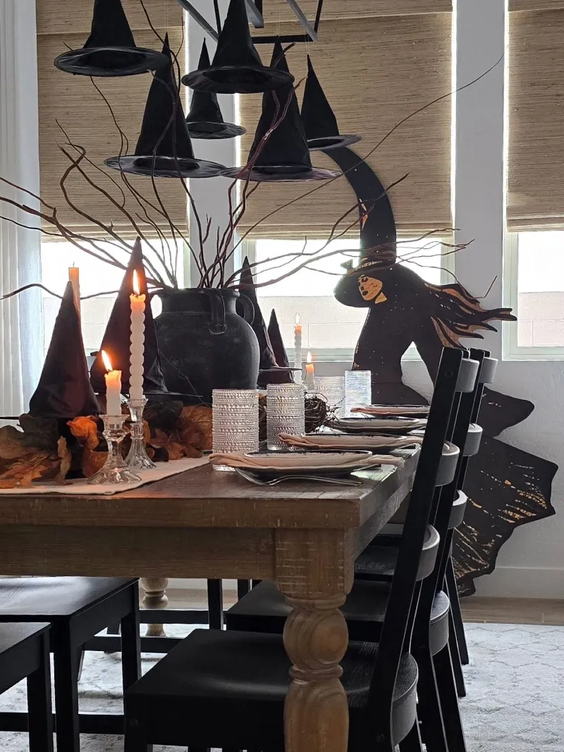 Floating Black Witch Hats above a Rustic Dining Table with Matte Black Earthenware Vase