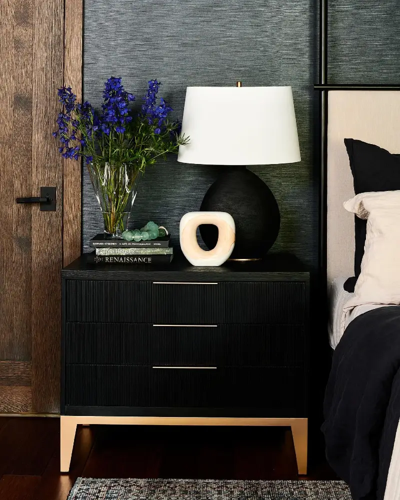 Fluted Black Nightstand with Deep Blue Linens and Textured Grasscloth Wallpaper