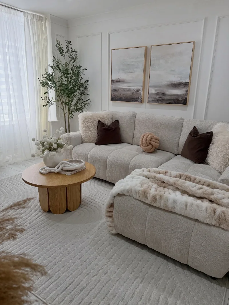 Framed Neutral Artwork with Cocoa Velvet Pillows and a Round Oak Coffee Table