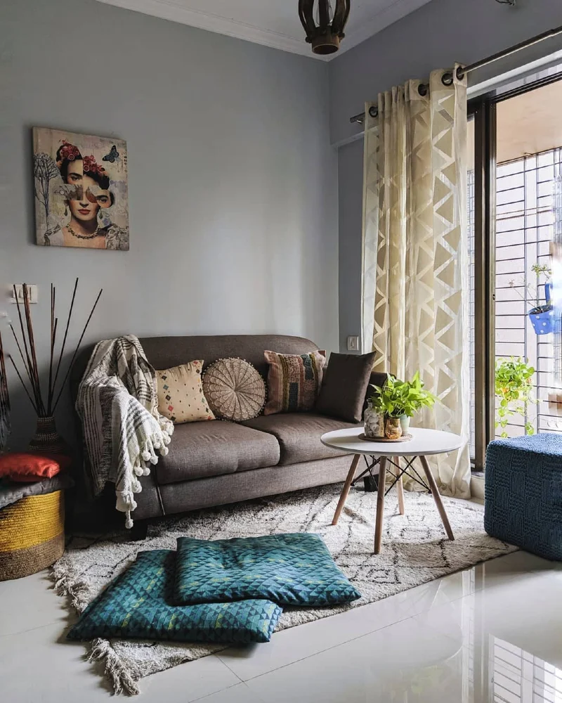 Gray Sofa with Floor Cushions, Blue Cube Pouf, and Round White Table