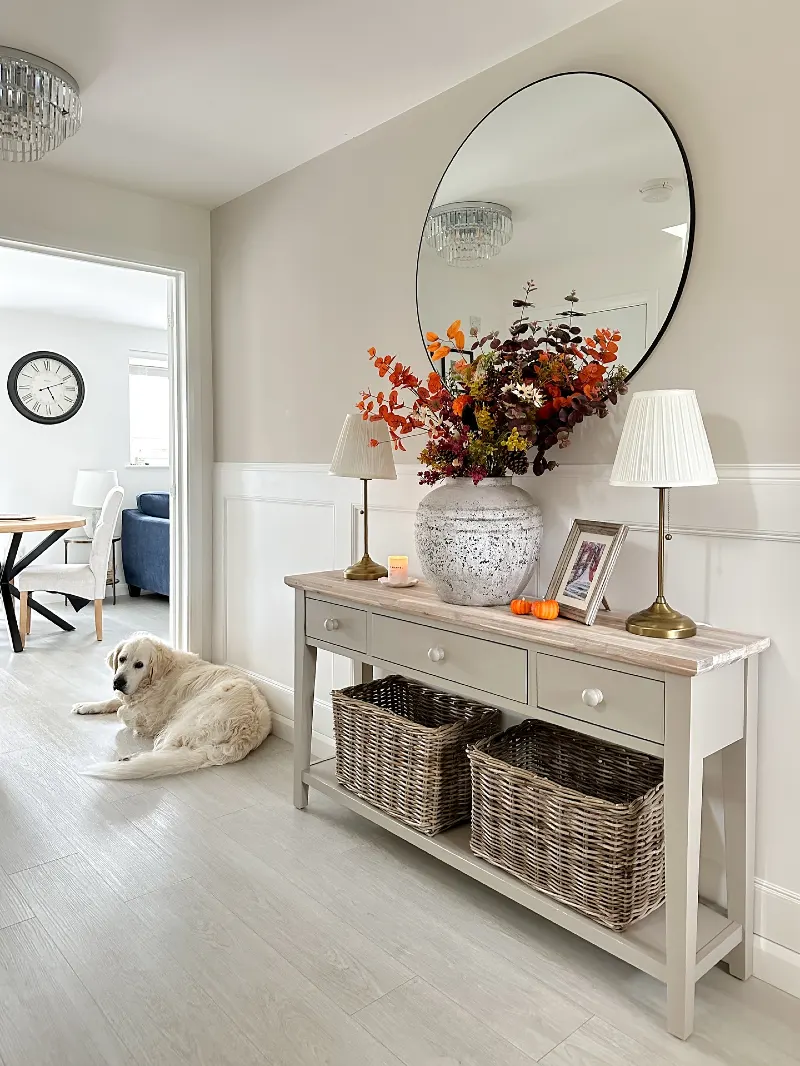Grey Console Table with Speckled Stoneware Vase, Pleated Brass Lamps, and Large Woven Baskets