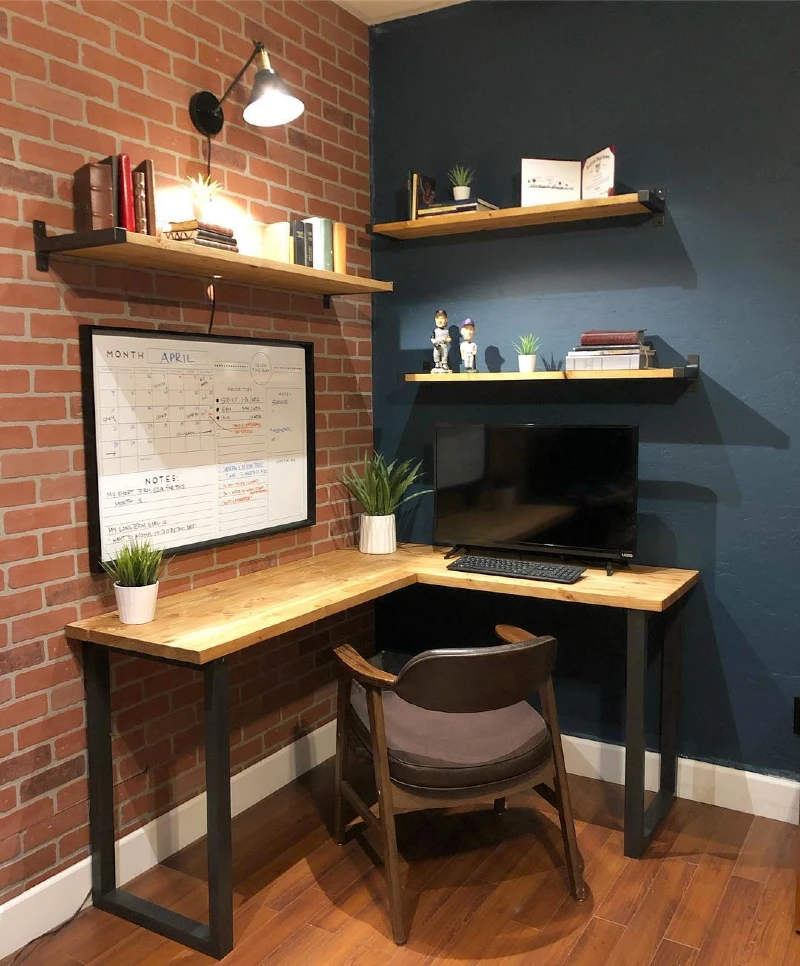 Industrial Corner Desk with Brick Accent Wall and Floating Wood Shelves