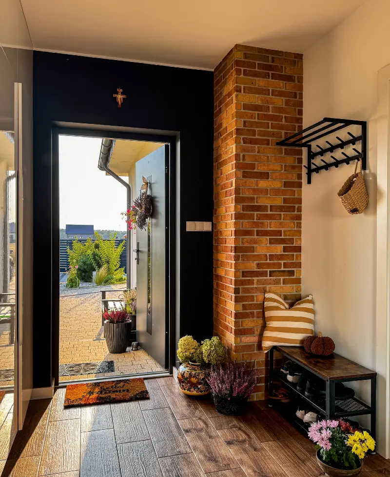 Industrial Shoe Bench with Striped Cushion, Exposed Brick Pillar, and Potted Autumn Florals