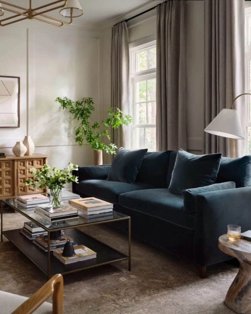 Ink Blue Velvet Sofa with Soft Gray Drapes and Warm Wood
