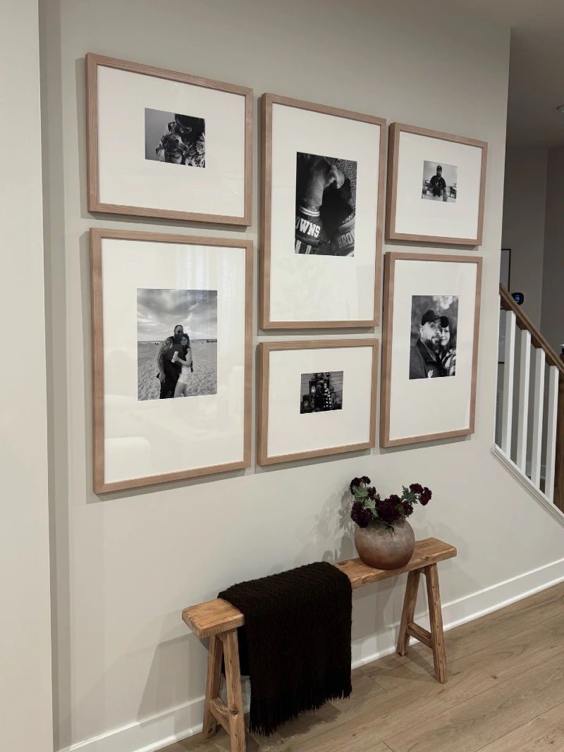 Light oak gallery wall with black and white portraits above a rustic wood bench