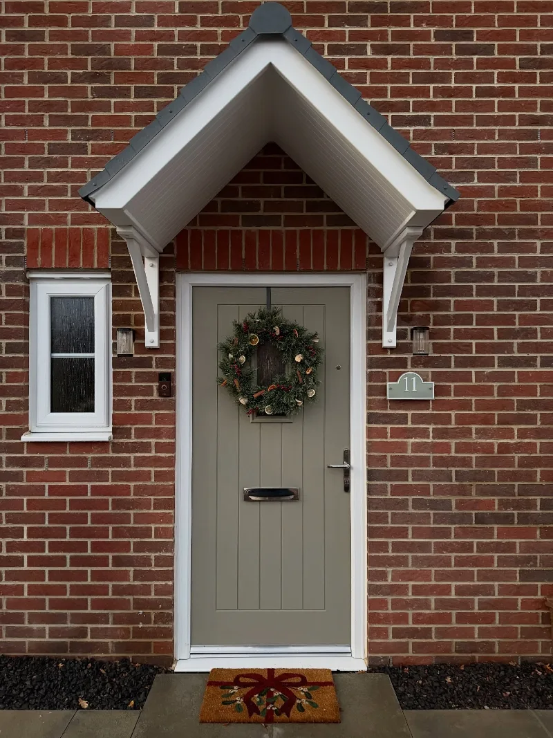 Muted Olive Front Door Beneath a Steep White Gabled Canopy