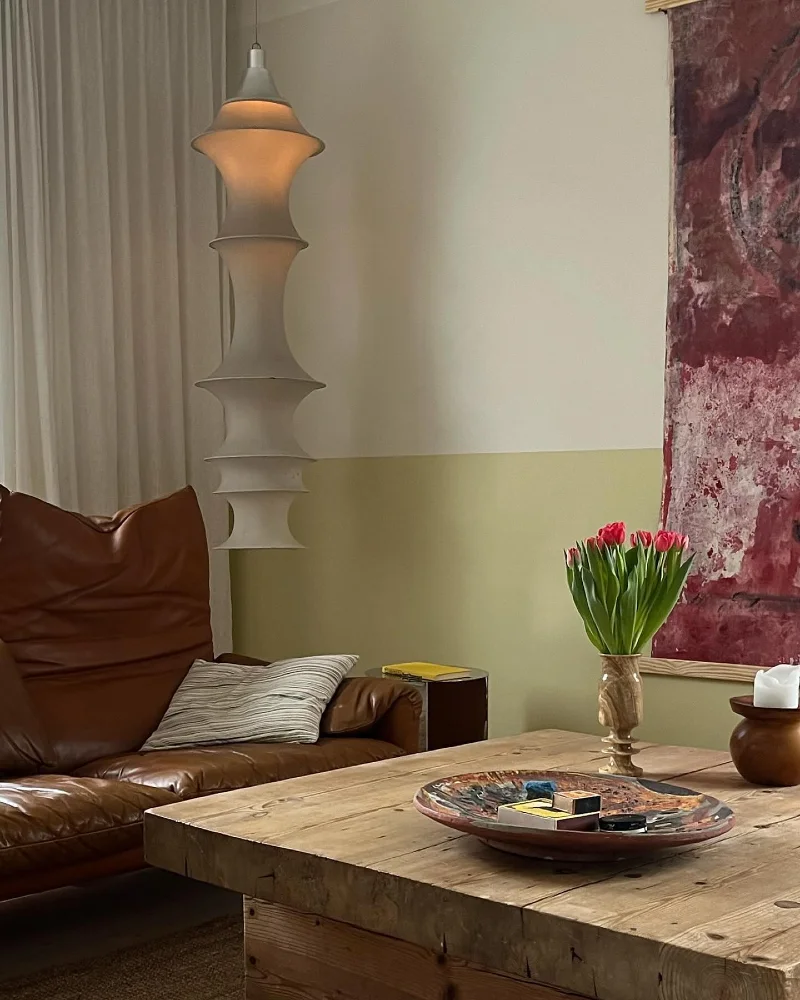 Muted Olive and Cream Two-Tone Wall with Brown Leather Sofa and Tiered Pendant Light