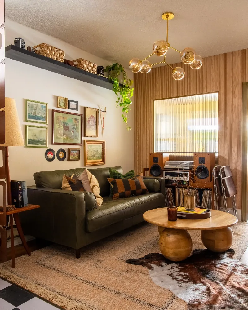 Olive Leather Sofa with Gallery Wall and Vertical Wood Slat Accent