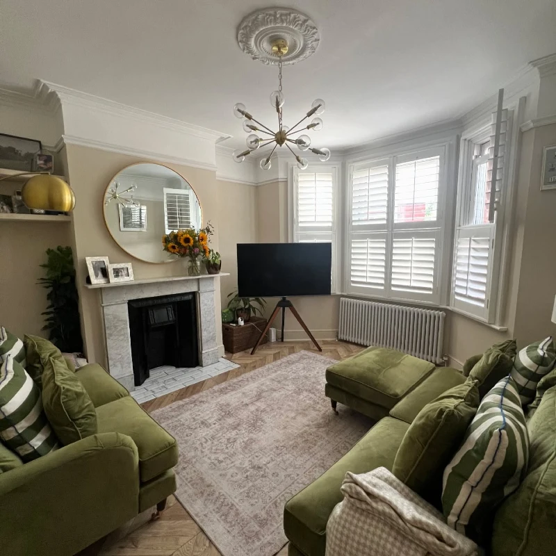 Olive Sage Velvet Sofas with Round Gold Mirror, Marble Fireplace, and Tripod TV Stand