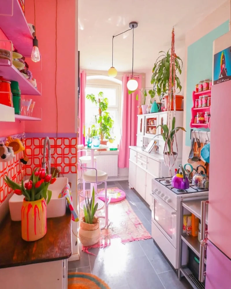Pink-Drenched Galley Kitchen with Geometric Backsplash and Hanging Greenery