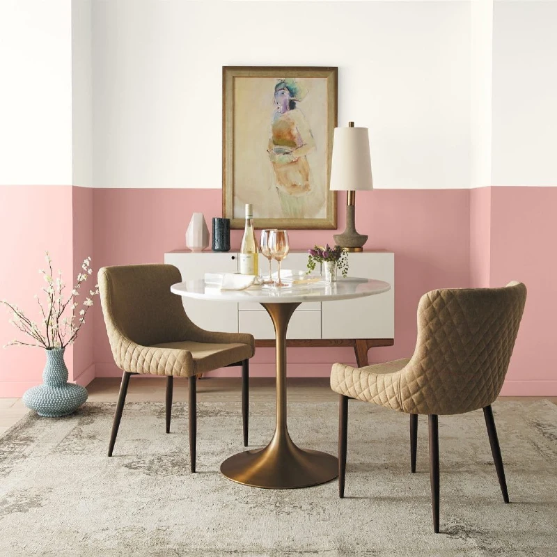 Rose Pink Half-Painted Wall with Round Brass Dining Table and Quilted Tan Chairs