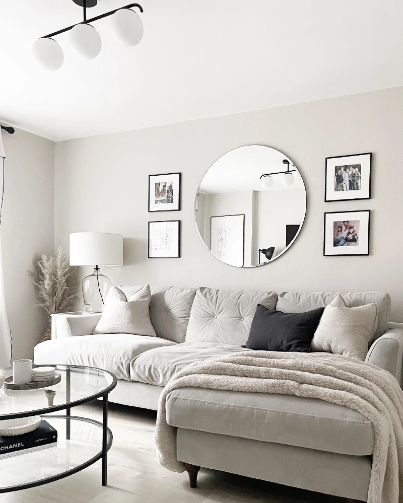 Round Frameless Mirror with Black Framed Gallery Prints and Cream Tufted Sectional