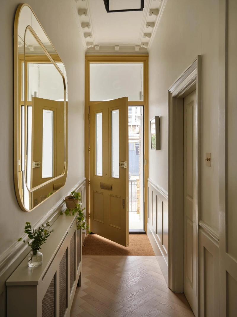 Rounded Rectangular Gold Mirror with Mustard Yellow Entry Door and Slender Radiator Cover