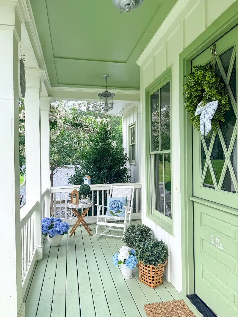 Sage Green Front Door with Matching Ceiling, Floor, and White Rocker