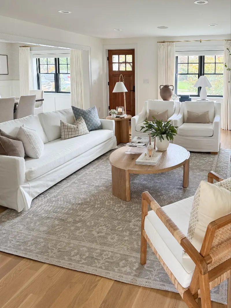 Slipcovered Armchairs with an Oval Oak Coffee Table and Black Window Frames