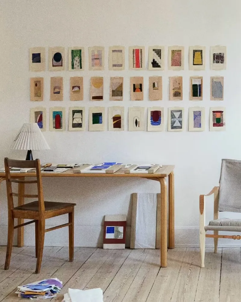 Staggered light wood floating shelves with layered art prints and trailing houseplants
