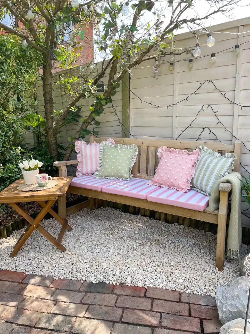 Timber Garden Bench with Pastel Striped Cushions Beneath a Flowering Tree