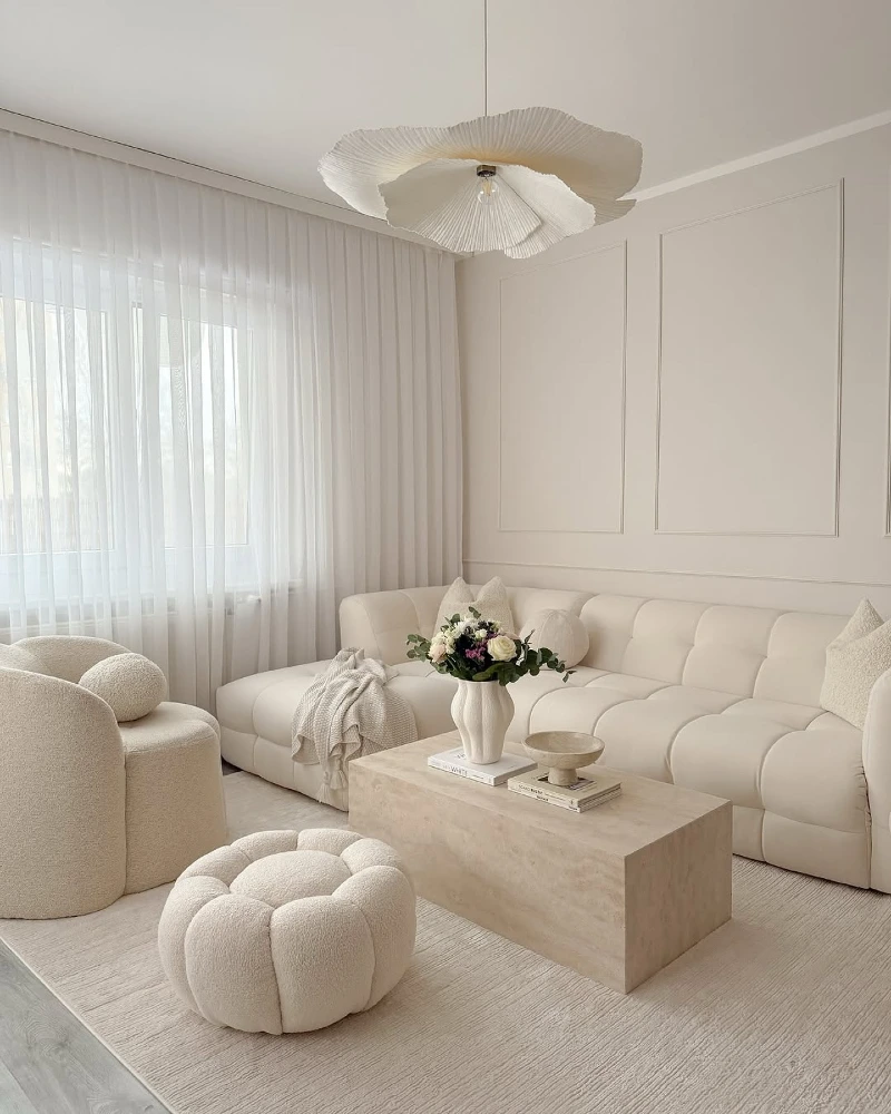 Tufted Cream Sofa with a Travertine Coffee Table and Sculptural Pendant