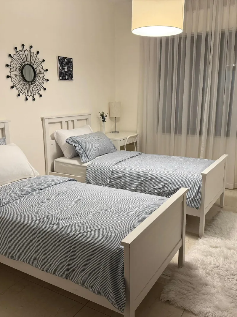 Twin White Beds with Pinstriped Bedding and Sheer Curtains