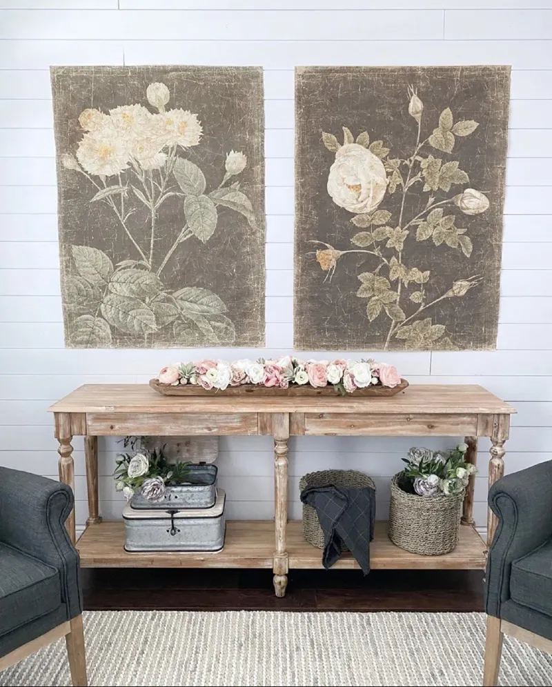 Unframed vintage botanical canvases mounted above a weathered wood console table