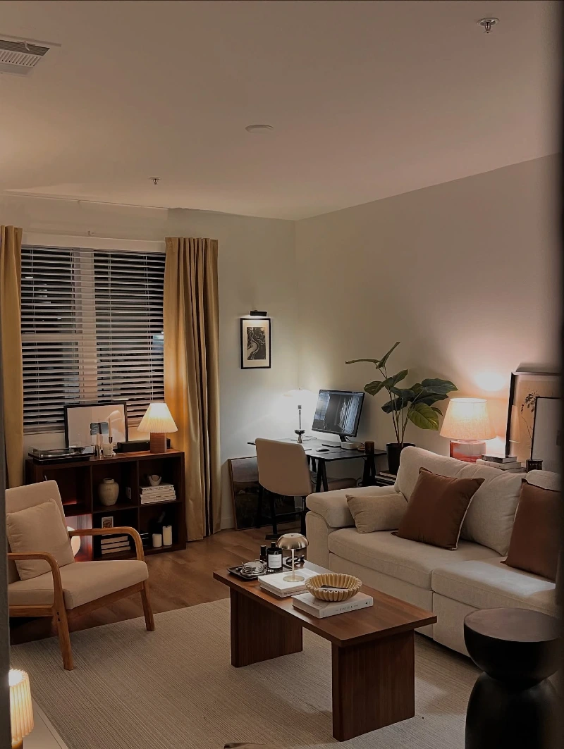 Warm Lamp Layers Around a Cream Sofa and Compact Work Desk