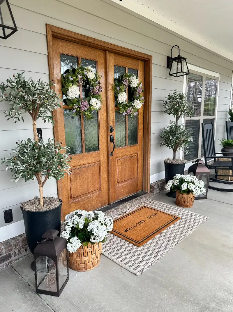 Warm Wood Double Doors with Floral Wreaths and Olive Topiaries