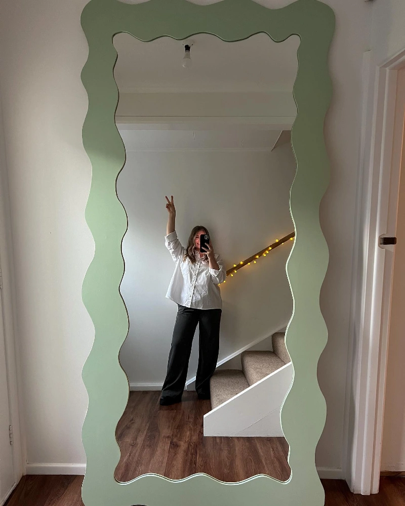 Wavy leaning floor mirror painted in soft mint green
