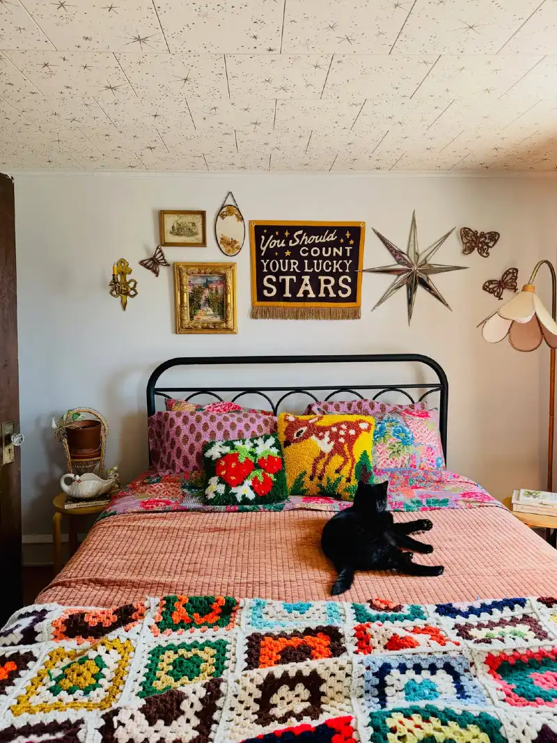 Whimsical Bedroom with Layered Quilts, Nostalgic Wall Art, and a Crochet Granny Square Blanket