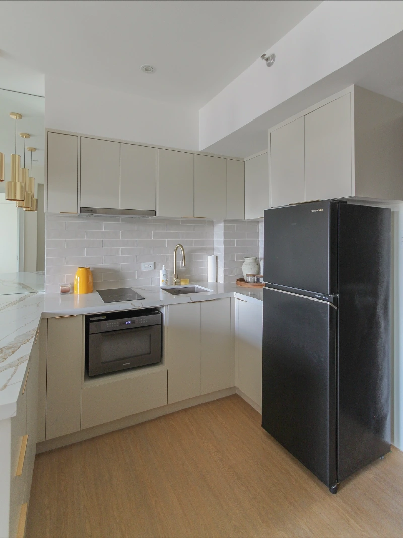 White L Shaped Kitchen with Black Appliances and Brass Hardware
