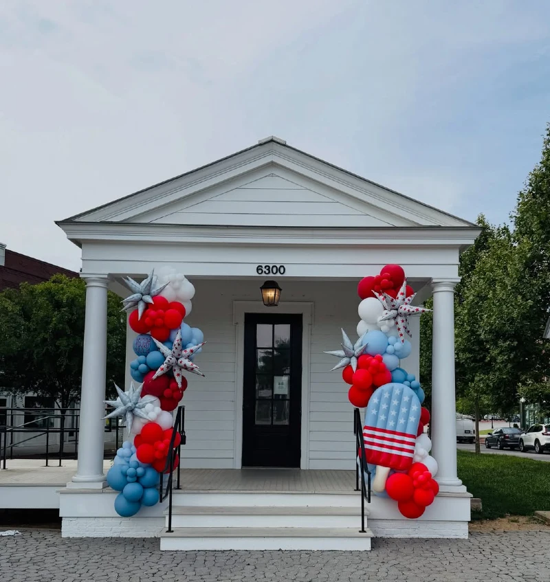 White Pediment Porch Wrapped in Patriotic Balloon Garlands and Popsicle Accent