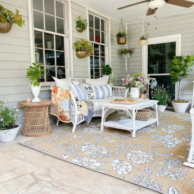 White Wicker Settee with Floral Patterned Rug and Hanging Potted Plants