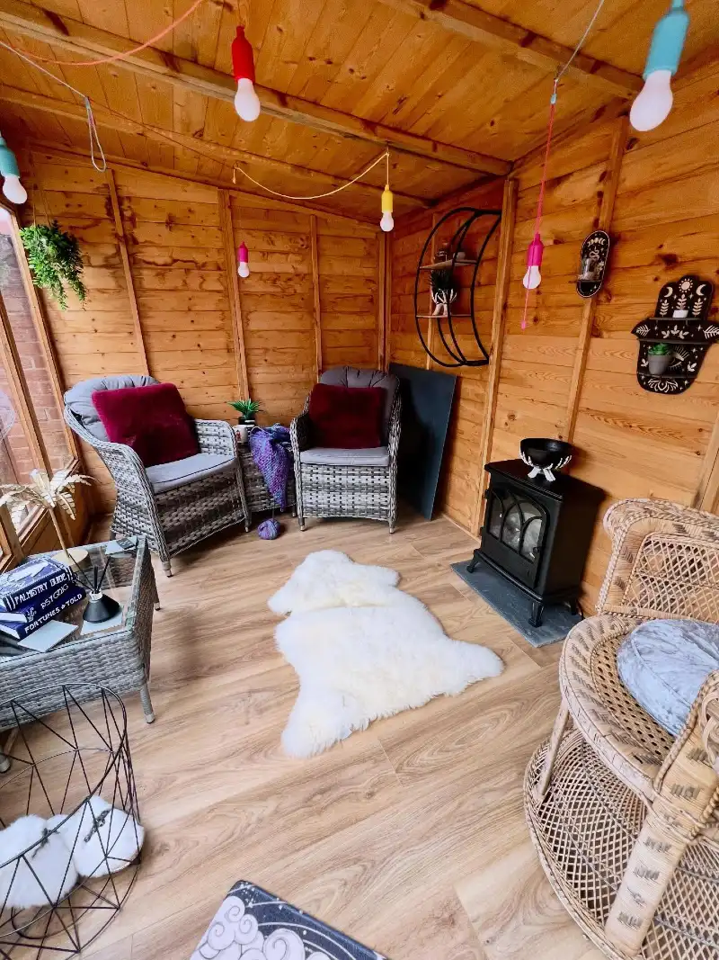 Wood-Paneled Shed Cabin with Wicker Armchairs and Colorful Festoon Bulbs