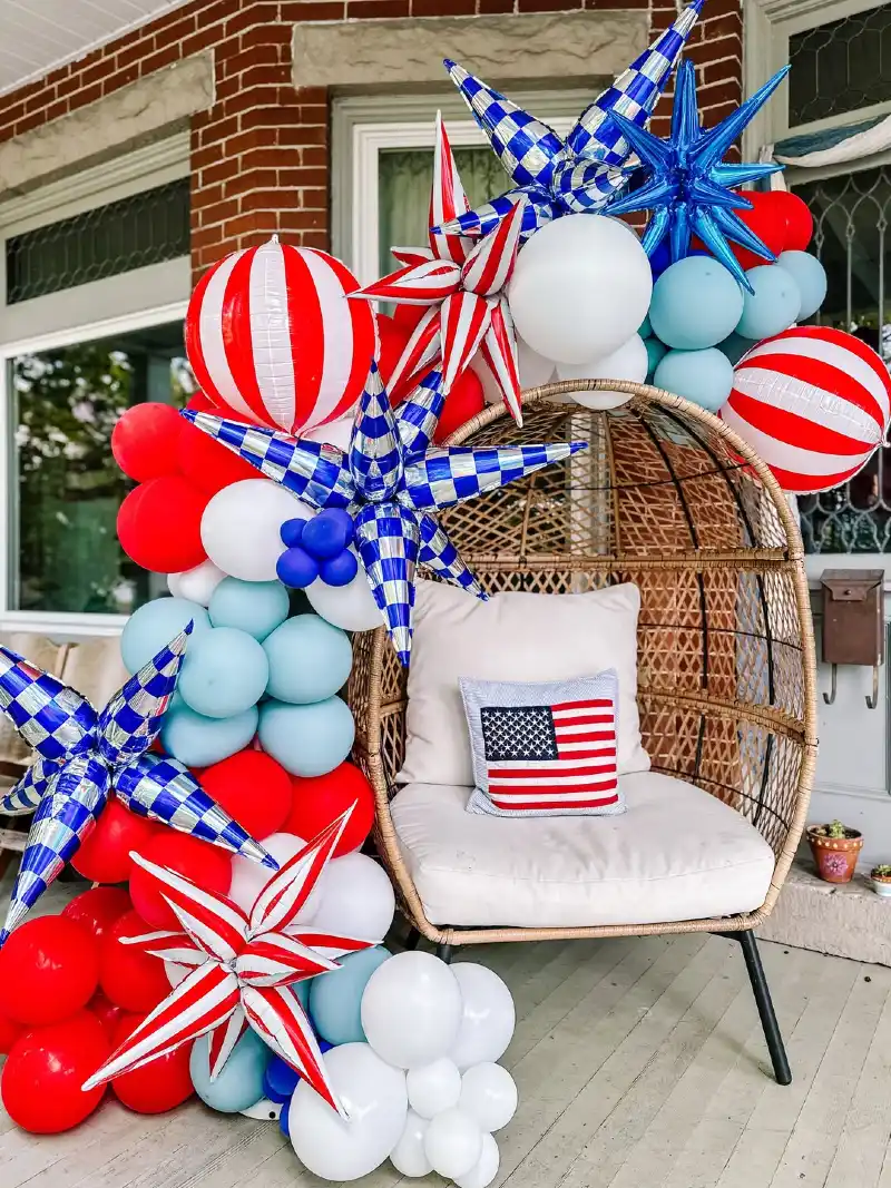 Woven Egg Chair Framed by Patriotic Balloon Arch and Metallic Stars