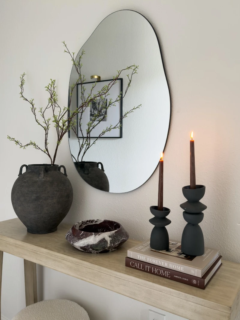 Asymmetrical Wall Mirror and Dark Ceramic Candleholders on Wooden Console Table