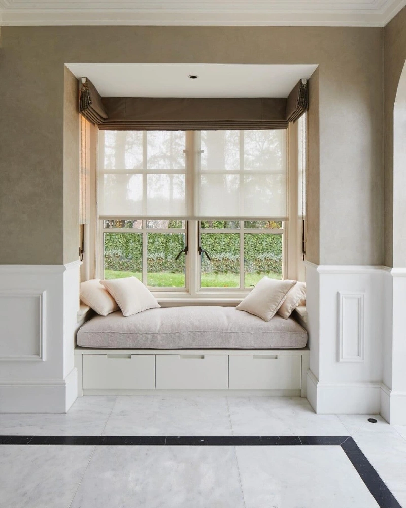 Brown Roman Shades Layered with Soft Sheers in a Window Alcove