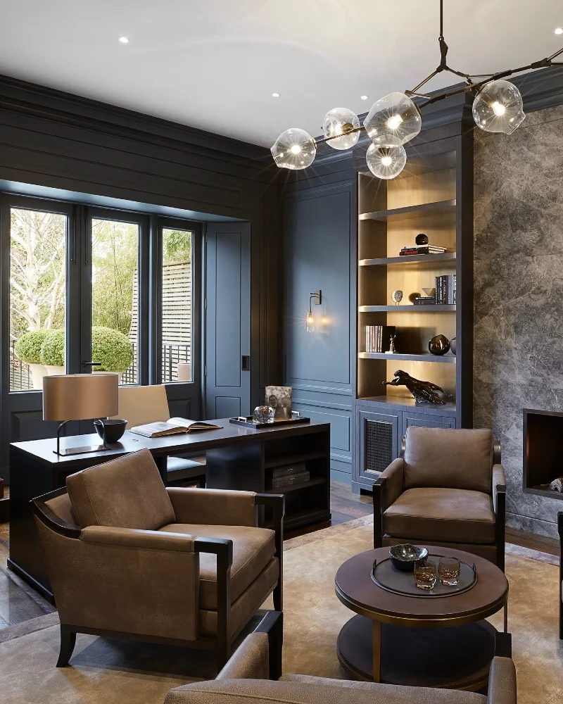 Deep Blue Paneled Study with Leather Club Chairs and Lit Bookcase