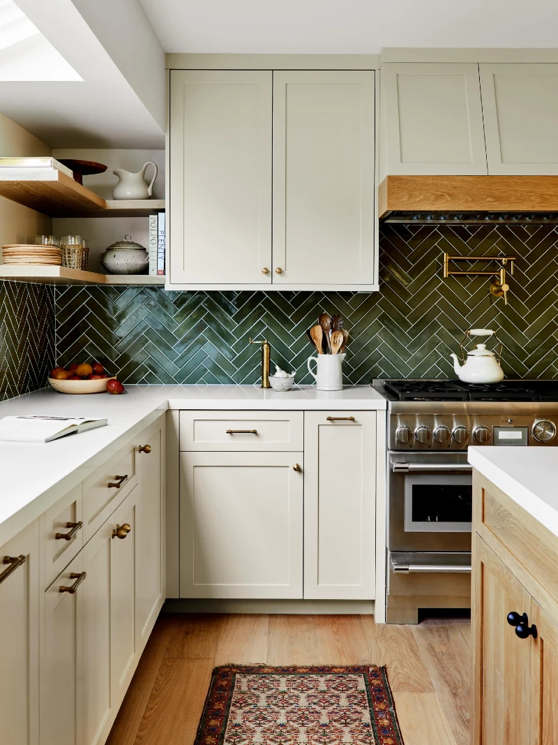 Deep Olive Herringbone Tile with Cream Cabinets and Brass Pot Filler