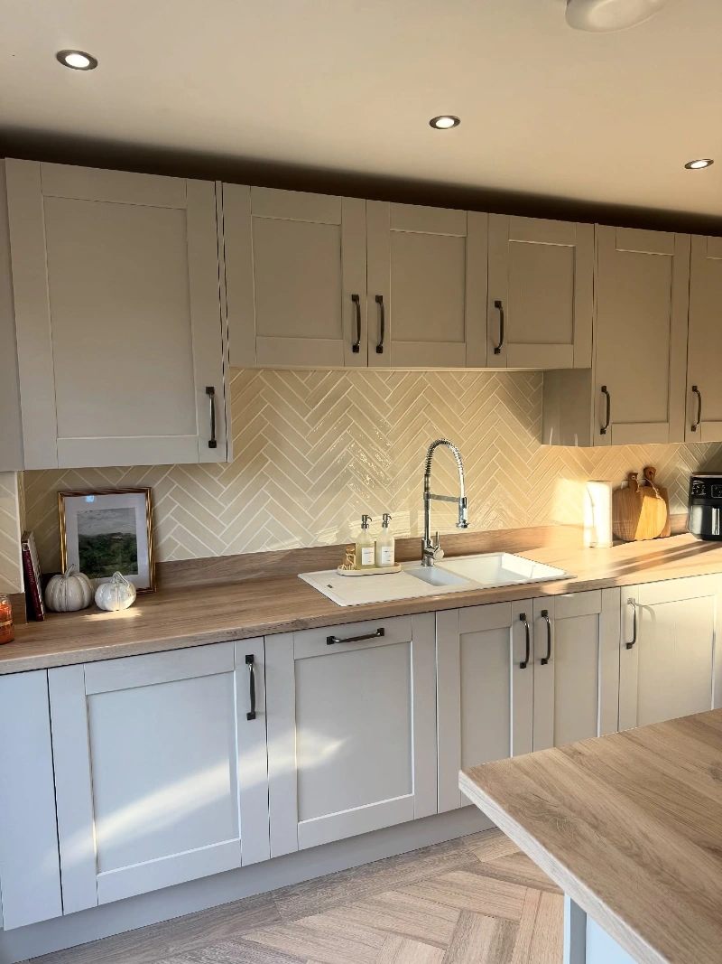 Glossy Beige Herringbone Tile with Warm Wood Counters