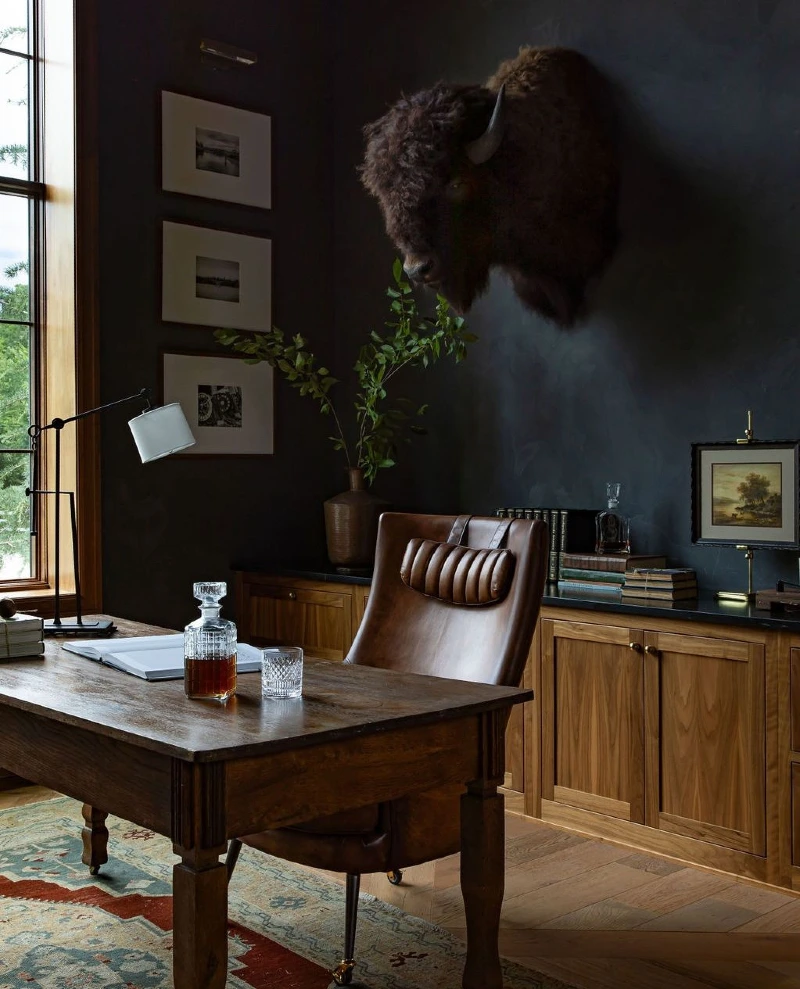 Moody Black Study with Bison Mount, Leather Chair, and Antique Desk