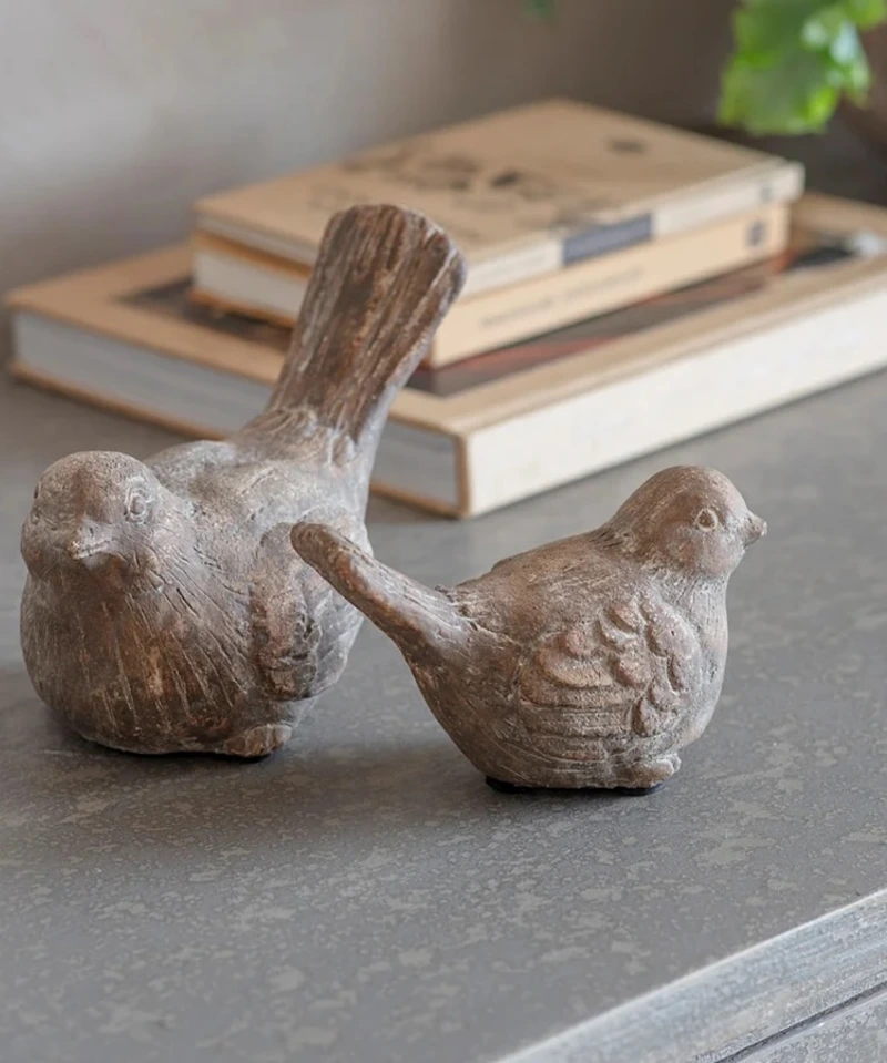 Rustic Carved Stone Bird Figurines Resting in Front of Neutral Books
